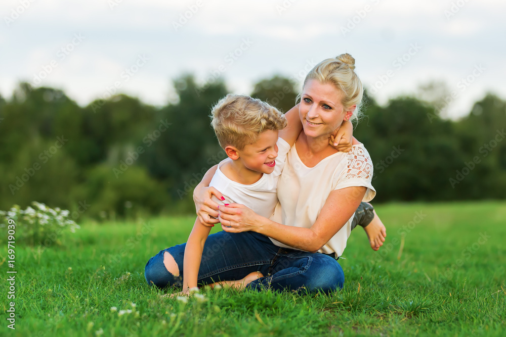 Fototapeta premium woman romps with her son on the grass
