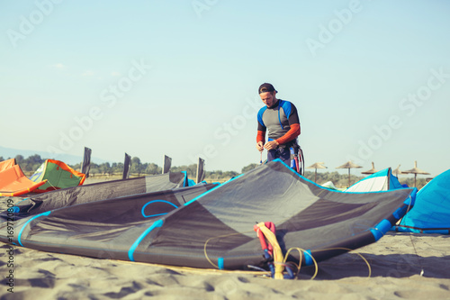Man sufrers in wetsuits with kite equipment for surfing.