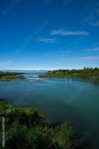 Iceland - Natural blue stream flowing into the ocean between green landscape at blonduos