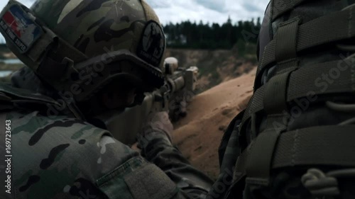 American soldiers in military camouflage lying on sand and shooting terrorists