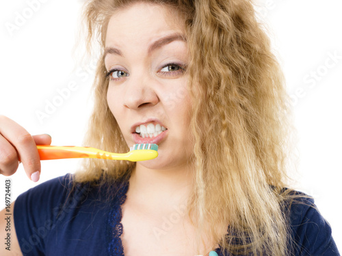 Grumpy tired woman brushing teeth, isolated