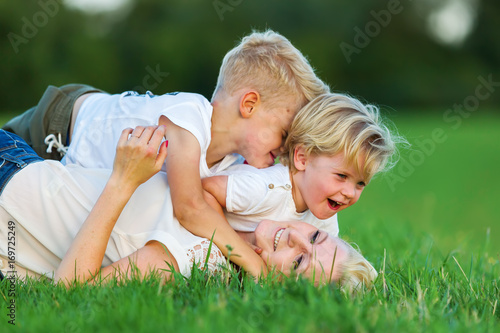 Fotografía woman romps with her two sons on the grass