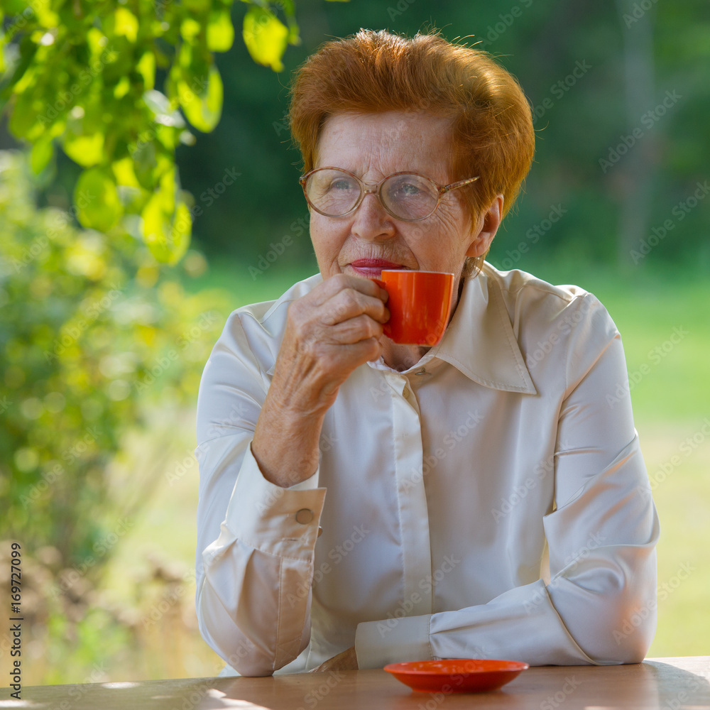 Fototapeta premium smiling woman in glasses is drinking coffee outdoors.