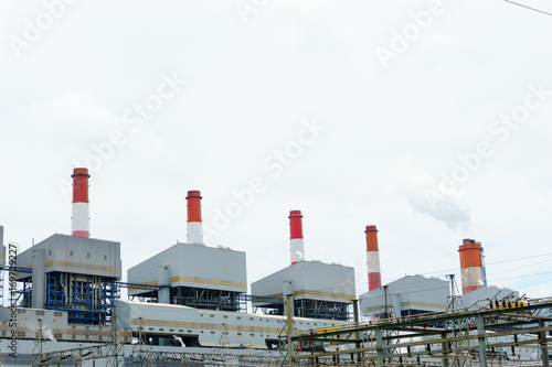 high voltage electricity station and 500 KV pylon and group of coal fired power plant and stack with blue cloudy sky, electricity concept