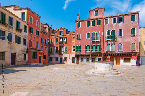 Typical square of Venice. Colorful old Venetian houses with green wooden shutters on the windows and stone pavement.