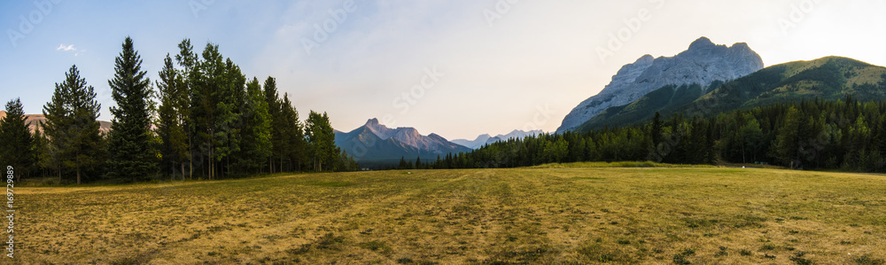 a panorama of mountains in Canada with a grass field