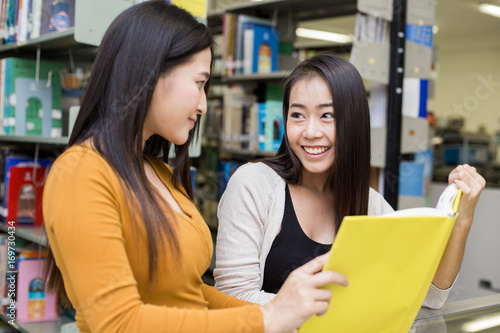 Woman in the foreground is reading a books. Young Asian Woman are reading in the modern library with Happy emotion. People with Education concept.