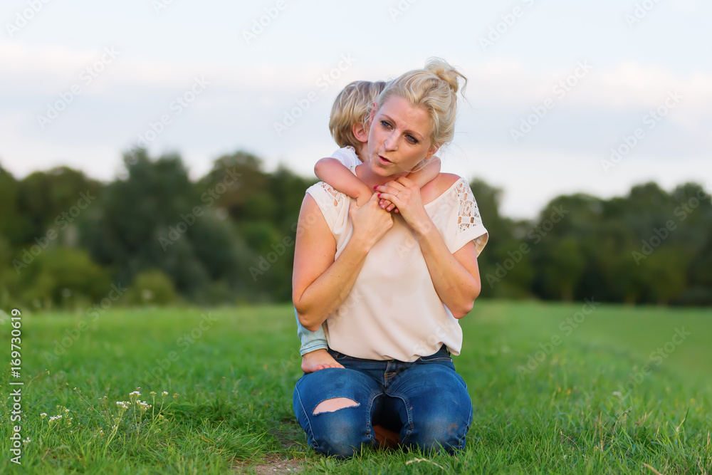 Fototapeta premium woman romps with her son on the grass