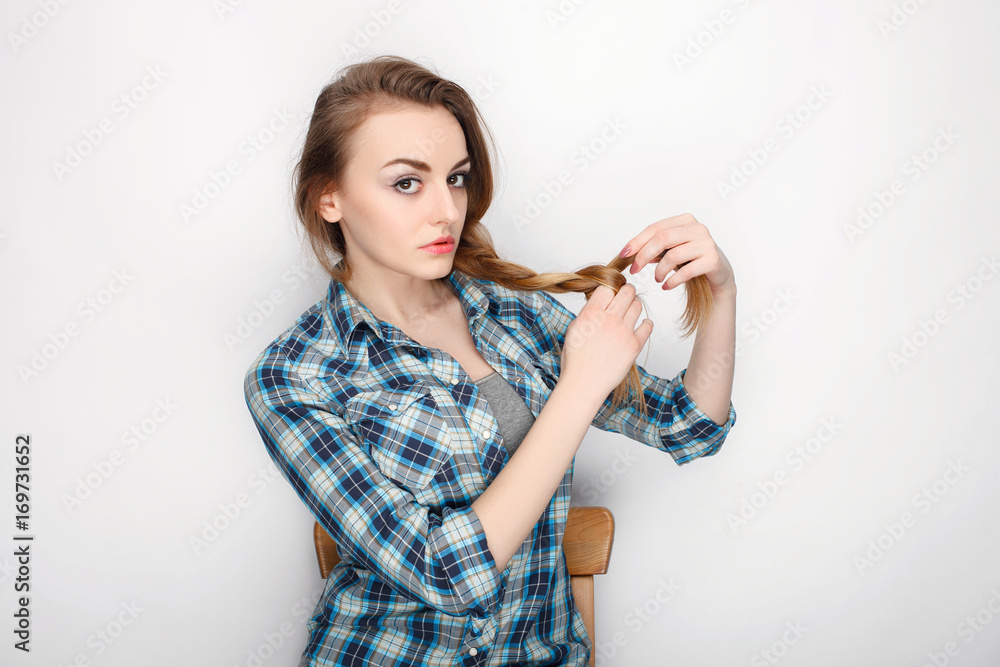 Beauty portrait of young adorable fresh looking blonde woman with high bun hair chaos in blue plaid shirt. Emotion and facial expression concept. Beauty portrait of young adorable fresh looking blonde woman with high bun hair chaos in blue plaid shirt. Emotion and facial expression concept.
