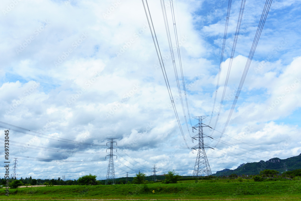 high voltage electricity pylon and transmission line in the field with blue sky and cloud