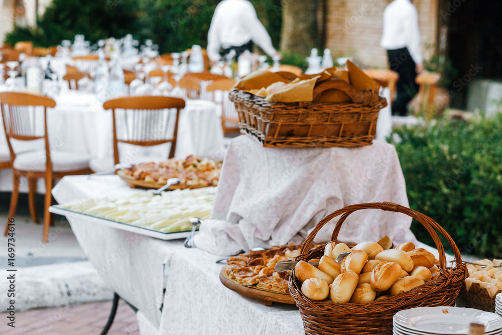 Baskets with different kinds of bread stand on long white table