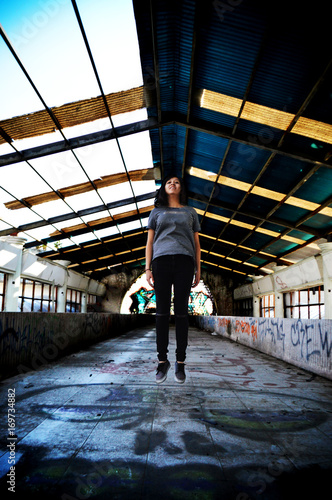 hermosa joven niña brincando en un lugar abandonado lleno de grafittis
