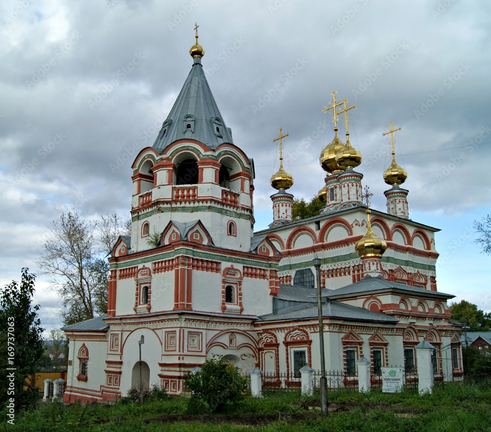 A small white-red ancient Orthodox temple in Old Russian style with a bell tower