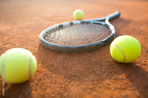 Close up view of tennis racket and balls on the clay tennis court, recreational sport © Khaligo