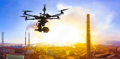 Professional drone flying over factory at sunset