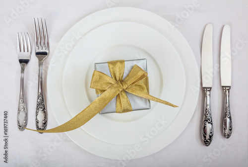 Formal table setting and a gift on white background