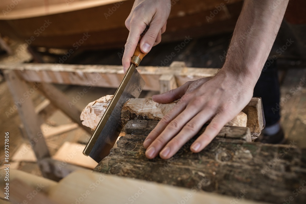 Mid section of carpenter cutting wooden log Mid section of carpenter cutting wooden log