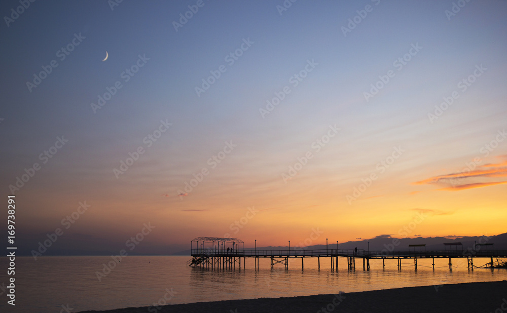 Colorful Sunset and moon from over pier