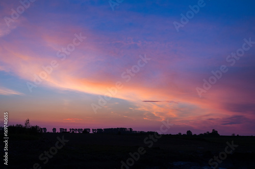 Natural Sunset Sunrise Over Field Or Meadow. Bright Dramatic Sky And Dark Ground. Countryside Landscape Under Scenic Colorful Sky At Sunset Dawn Sunrise. Sun Over Skyline  Horizon. Warm Colours.