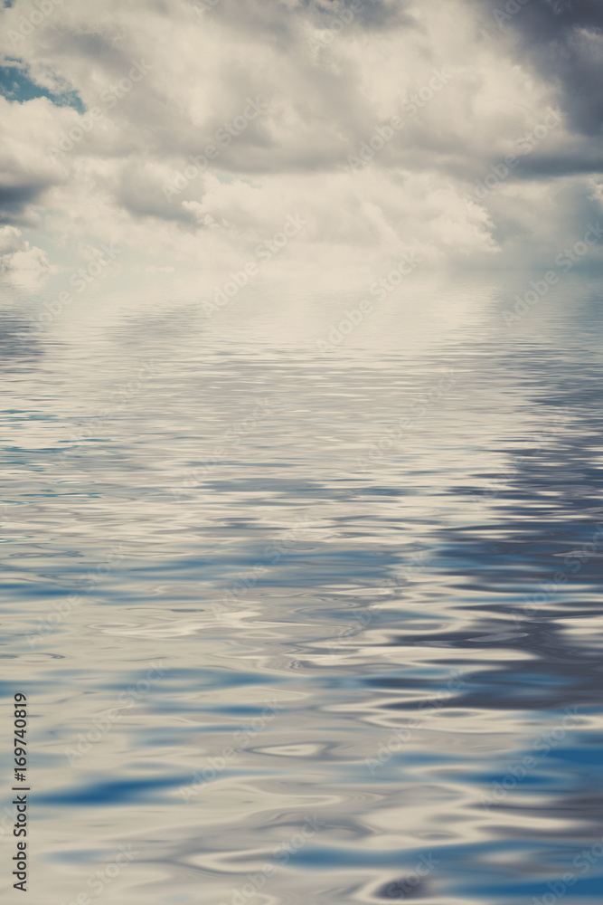 Water background with reflections of cloudy sky