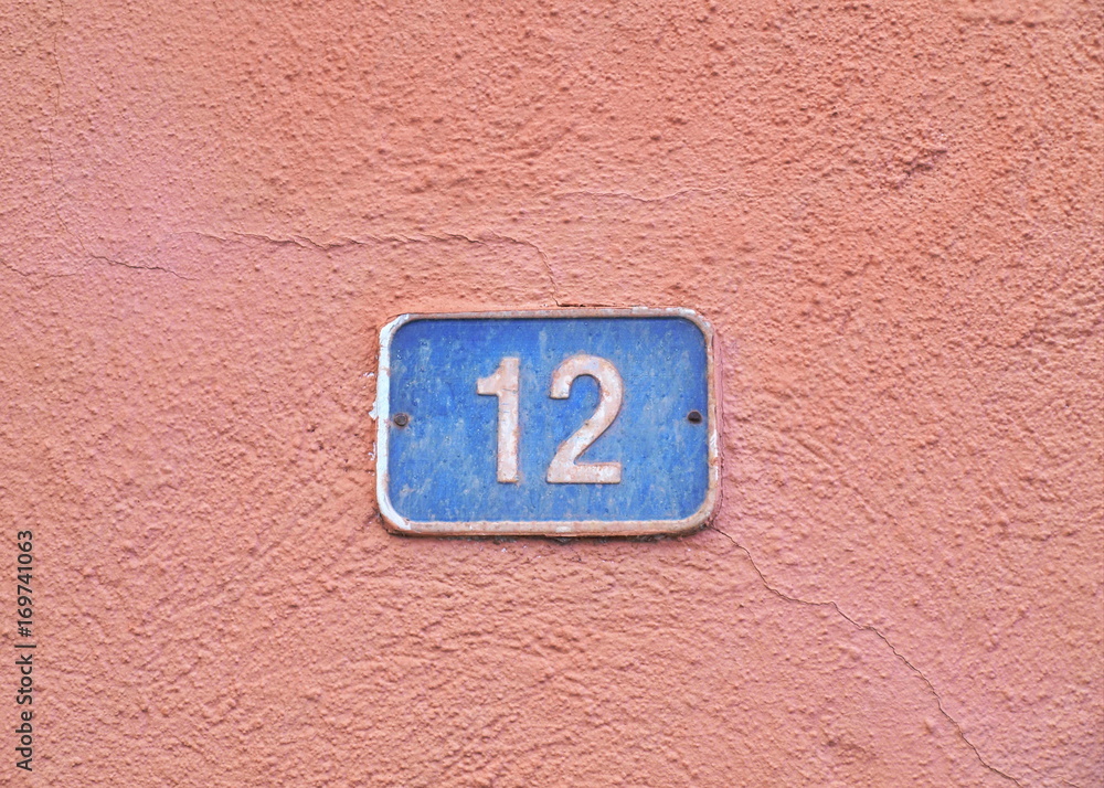 Hausnummer 12 blaues Schild auf rosa Wand Hausnummer 12 blaues Schild auf rosa Wand
