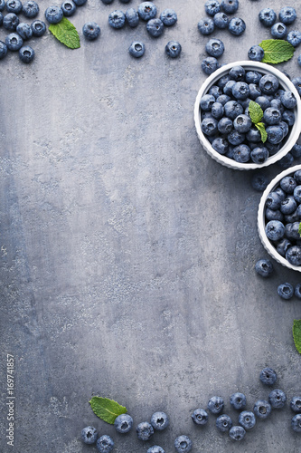Ripe blueberries in bowls on grey wooden table