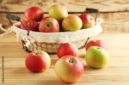 Ripe and sweet apples in basket on wooden table