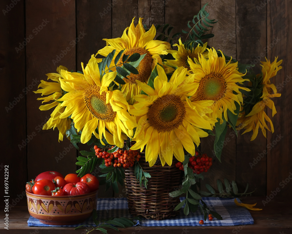 Fototapeta premium Sunflowers and tomatoes. Rustic still life of flowers and vegetables.