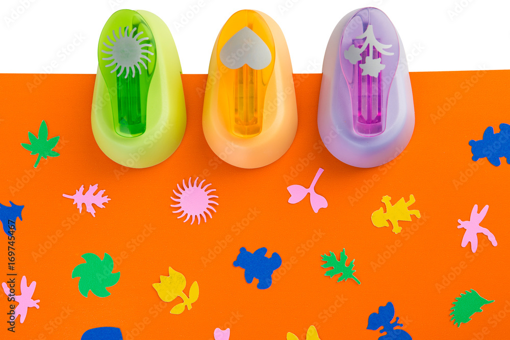 Three figure staplers on orange paper Three figure staplers on orange paper