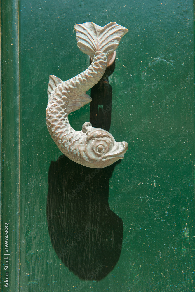 Fototapeta premium Close-up view of the fish shaped knocker on a green wooden door