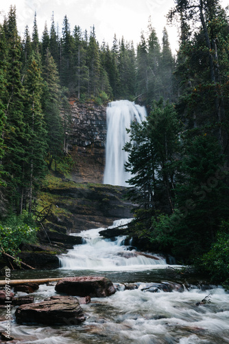 Waterfall and river surrounded by pine trees 