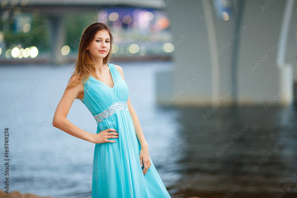 Beautiful young girl in a light blue dress on the beach