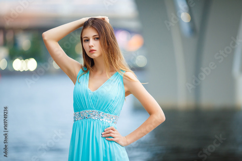 Beautiful young girl in a light blue dress on the beach