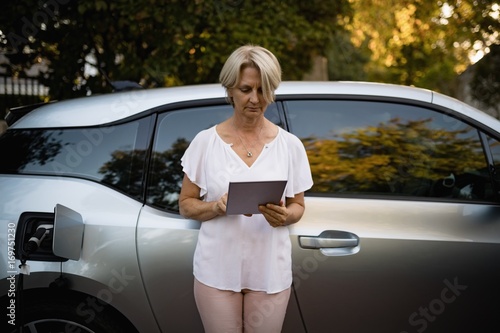 Woman using digital tablet near car photo