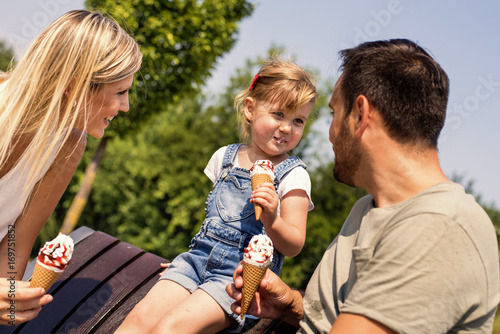 Happy young family eating ice cream and having fun outside