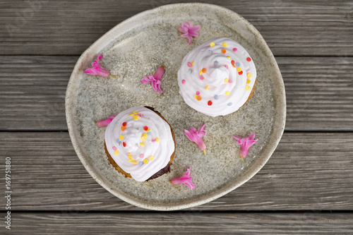 Cute homemade cupcakes and hyacinth flowers on a plate on a rustic wooden table, top view
