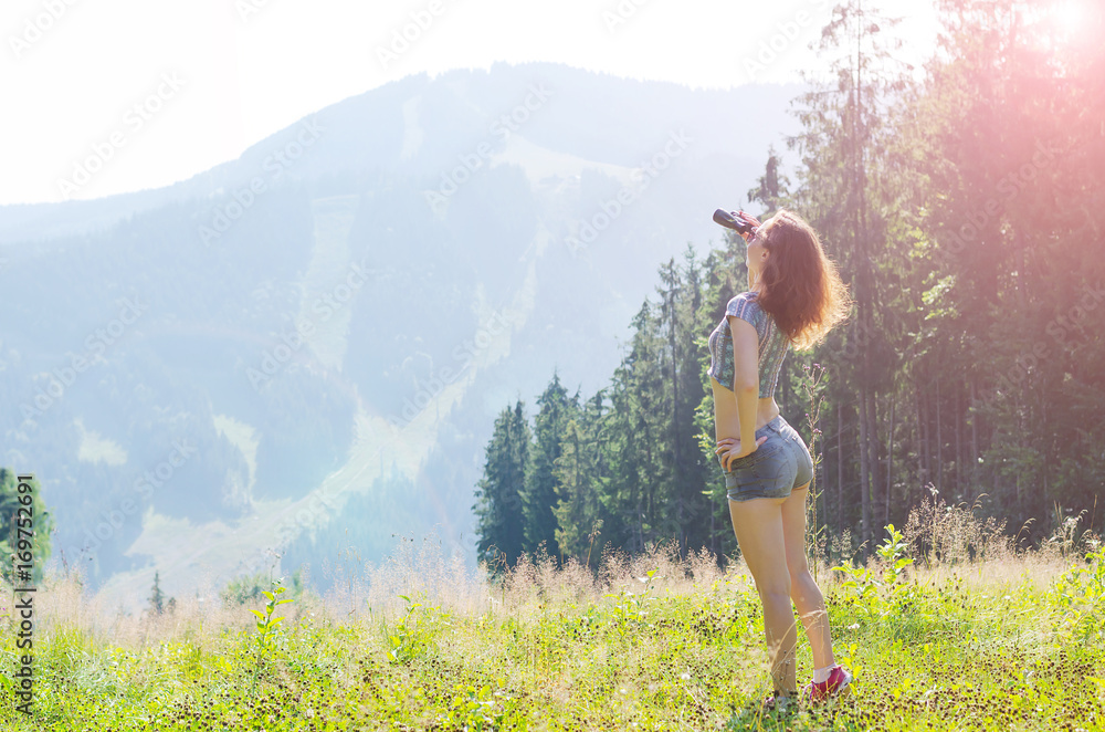 Young woman looks at the mountains through binoculars, outdoor activities, free space.