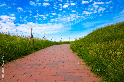 Brick pathway leading across green grass fields