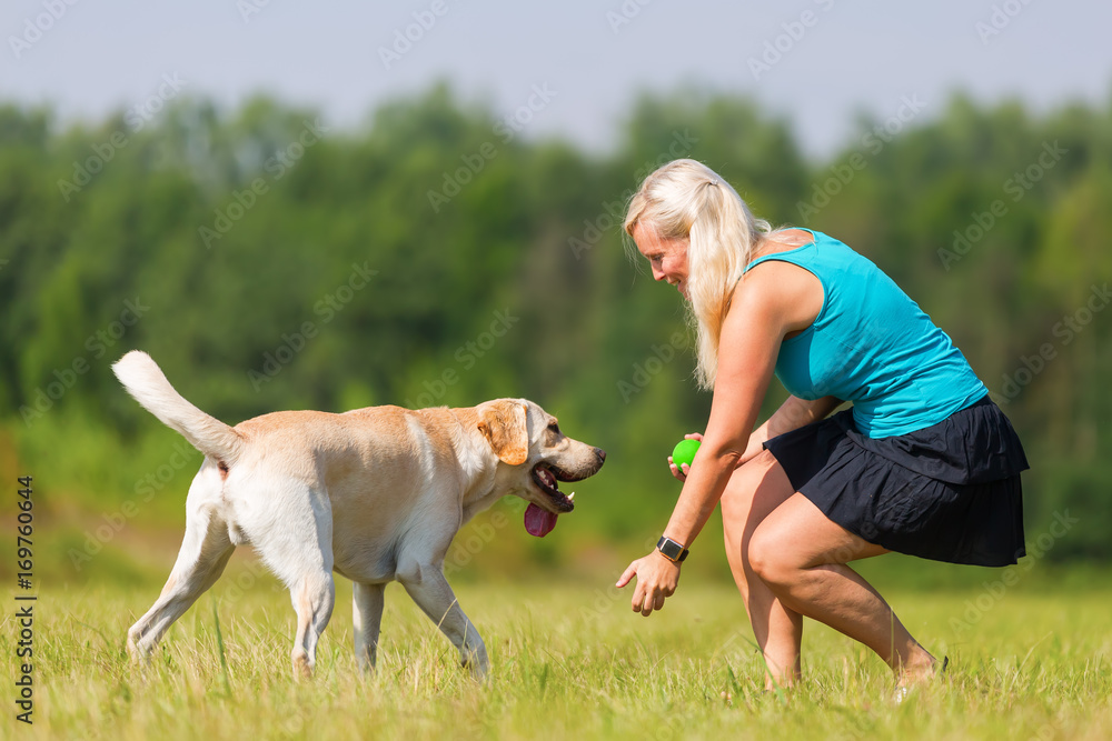 pretty woman plays with her labrador retriever outdoors