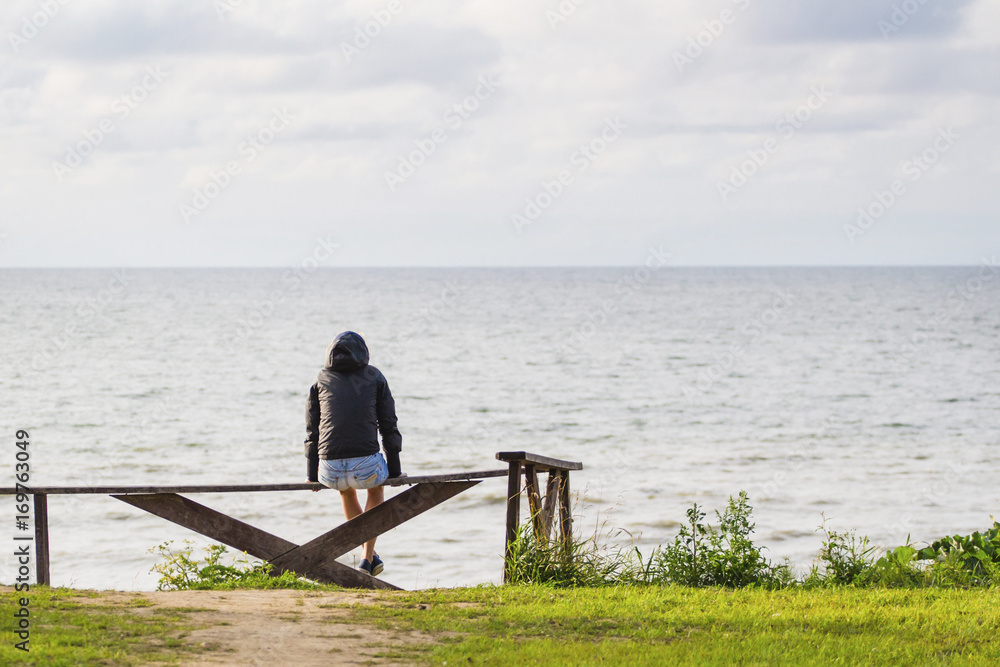 the girl sits on a bench and looks at the sea