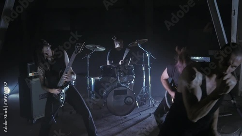 Concert rock band performing on stage with Frontman, guitarists and drummer. Music video punk, heavy metal or rock group.