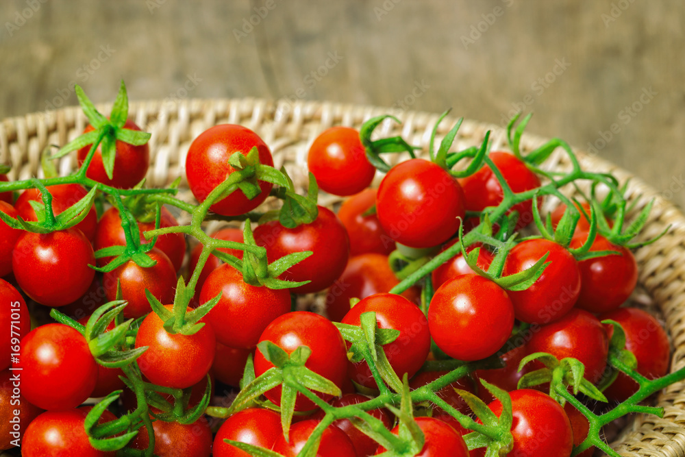 Fresh cherry tomato on wood basket.Close up lovely cherry tomato for background or wallpaper.Prepare fresh cherry tomato for home cooking look so delicious.Top view concept of cherry tomato in basket.