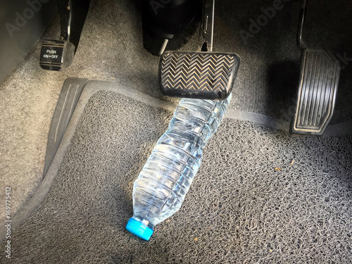 Water bottle getting stuck in the car accelerator and brake peddle demonstrating the danger of the inability to apply the brake or acceleration