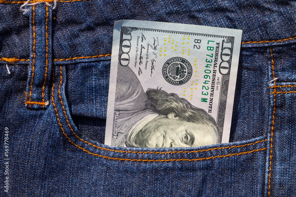 One hundred American dollars bill in the pocket of blue jeans One hundred American dollars bill in the pocket of blue jeans