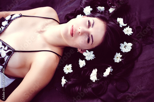 Fototapeta Naklejka Na Ścianę i Meble -  Pretty girl in the morning lies in the rays of light with white flowers in her hair, pensive and philosophical moods, reflections on beauty. The concept of harmony with oneself