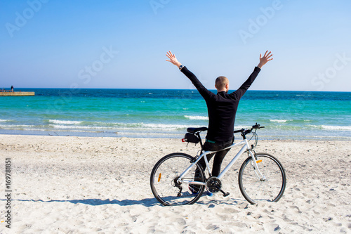 Bicycle rider relaxing on the beach in good weather 