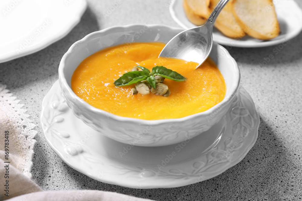 Bowl and spoon with delicious carrot soup on table Bowl and spoon with delicious carrot soup on table