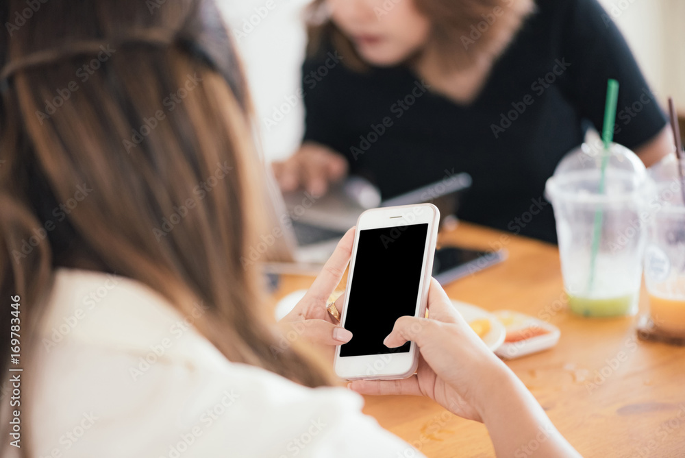Close up of Asian women's hands holding cell telephone with blank copy space scree for your advertising text message or promotional content, Concept : working, meeting, study, education in coffee shop Close up of Asian women's hands holding cell telephone with blank copy space scree for your advertising text message or promotional content, Concept : working, meeting, study, education in coffee shop