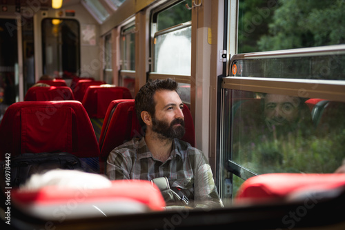 Young adult men commuter traveling alone by train seated in sunny summer day. photo