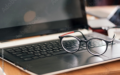 Vintage style glasses resting on a black laptop.